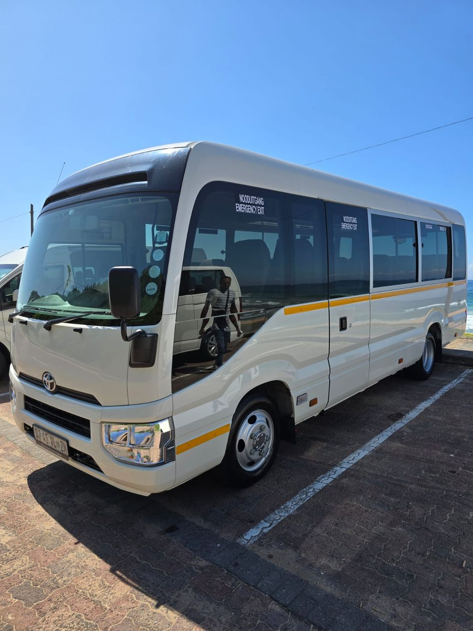 Toyota Coaster tour bus parked at the beachfront