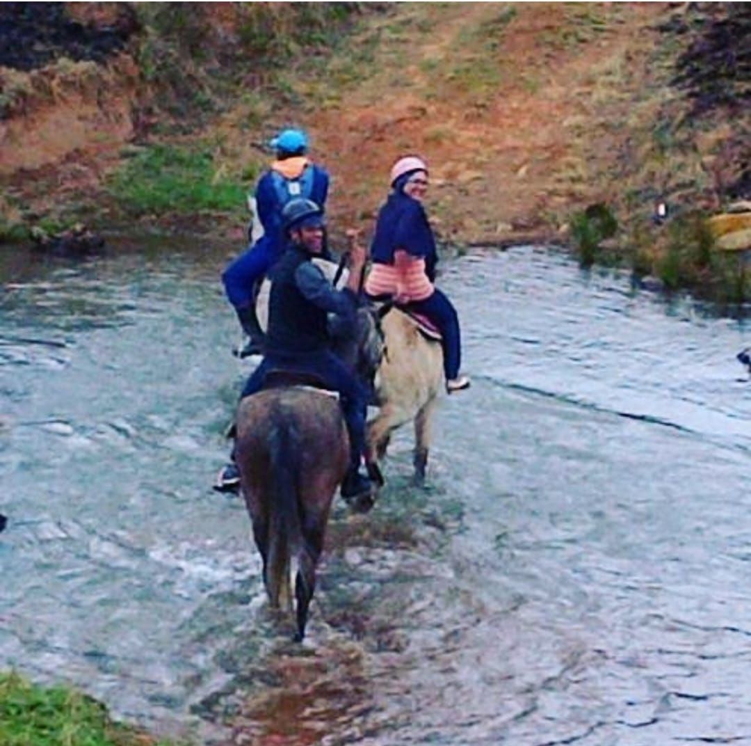 Guests horse riding through a river crossing in the KwaZulu-Natal Midlands